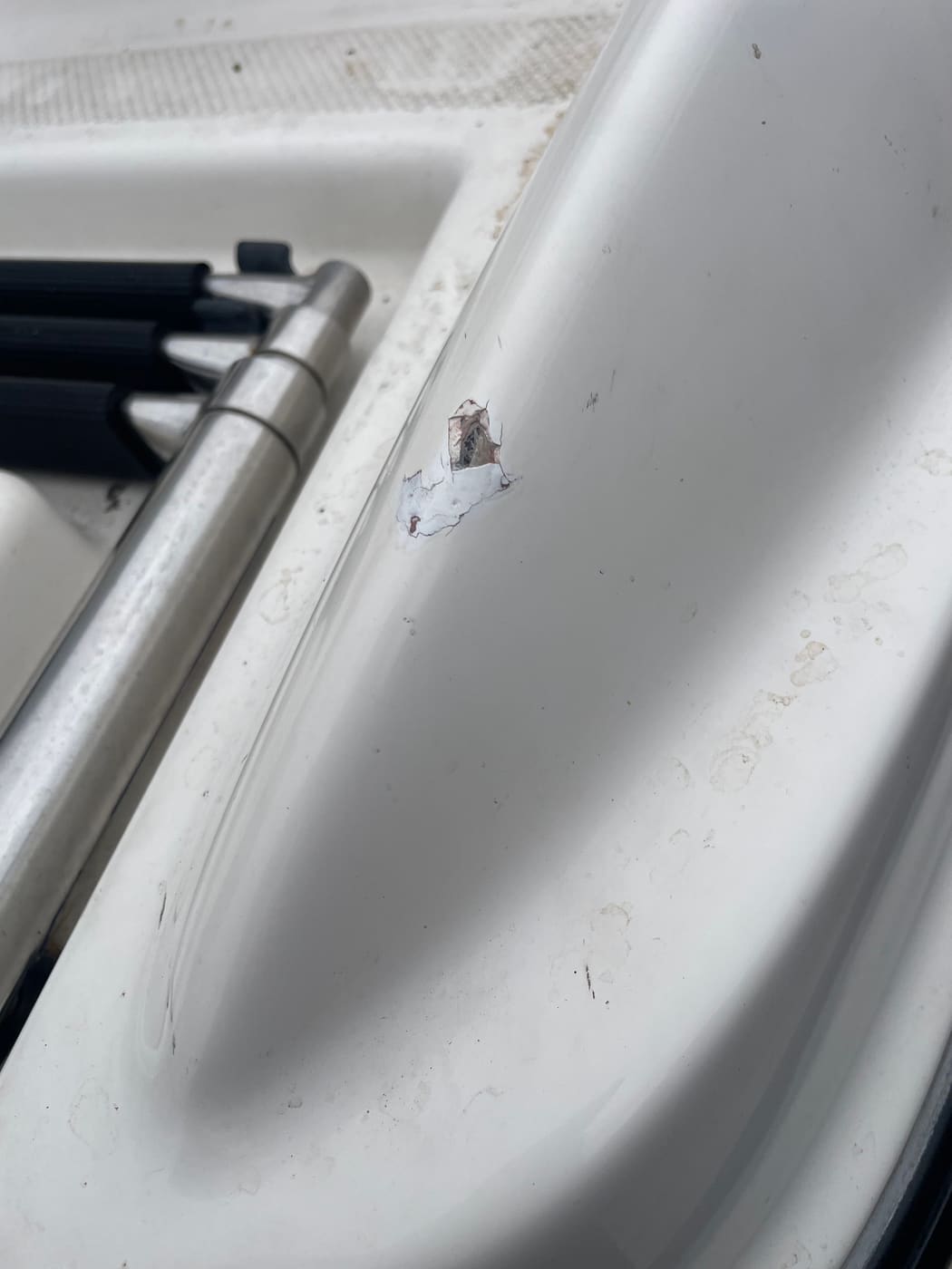 Chip through the gelcoat on a boat gunwale beside the grab rail before repair, Brisbane