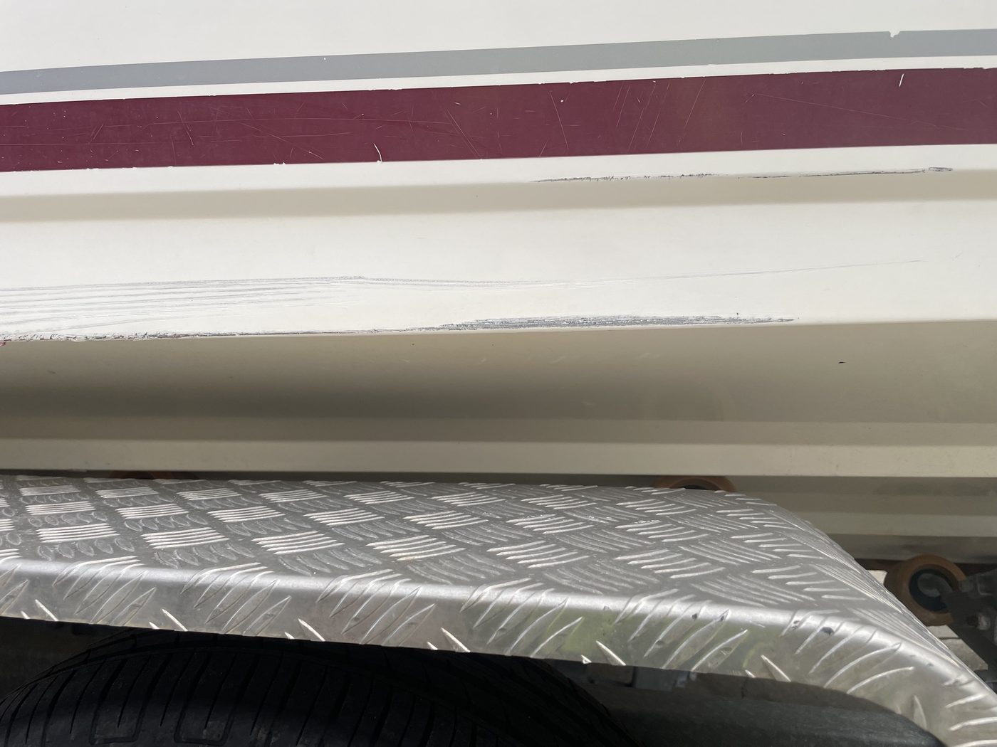 Deep scratch along a boat hull strake above the trailer guard before gelcoat repair, Brisbane